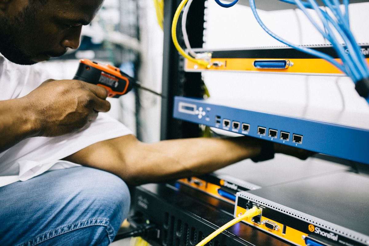 Network technician installing and terminating equipment in a commercial network rack